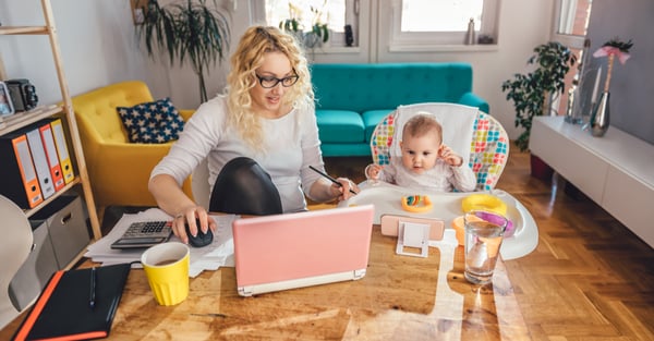 Mother working at home while taking care of her baby