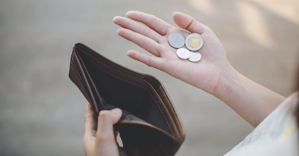 Person looking at an empty wallet and some coins