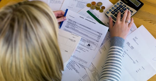 Woman with bills, coins, and a calculator laid out in front of her