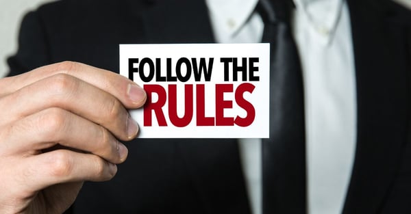 a businessman holding a card that says follow the rules