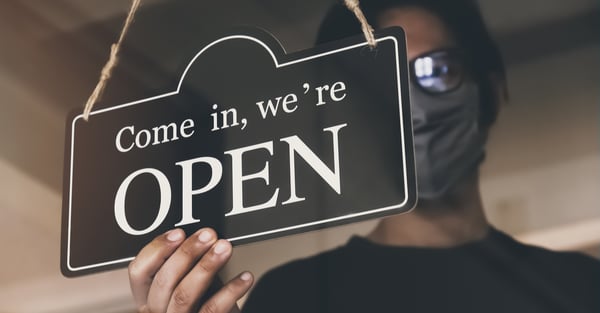 man_with_face_mask_turning_a_sign_on_a_door_shop