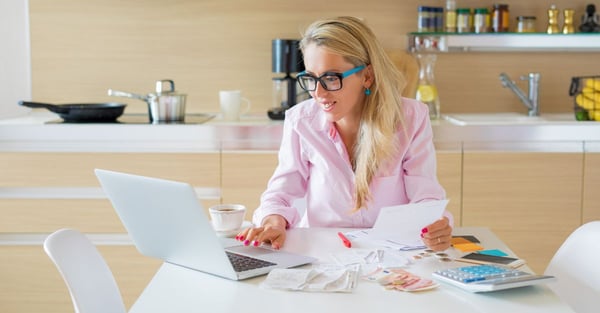 woman organising her finances using a computer, calculator and receipts